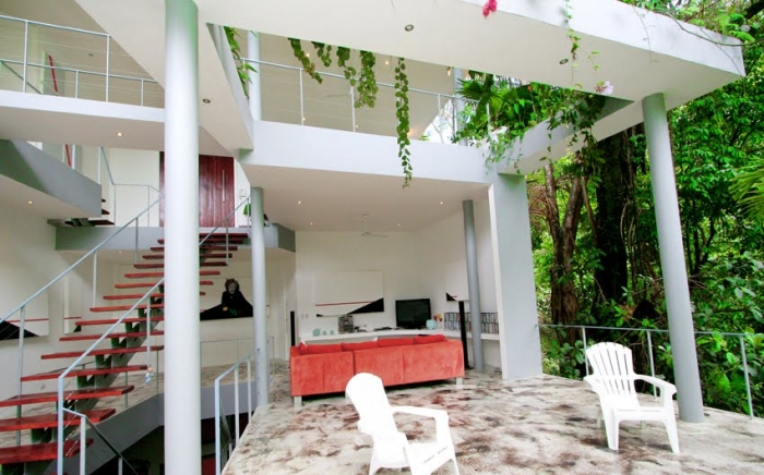 With vibrant tropical foliage covering the simple white architecture the rainforest really enters the home.